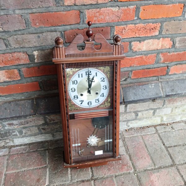 Antique mahogany wall clock with pendulum, a vintage timepiece.