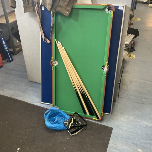 Mini pool table set with cues and balls on a green felt surface.