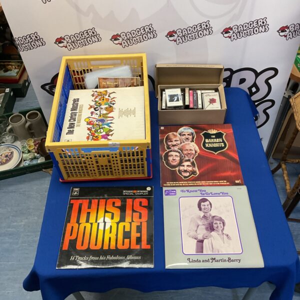 Crate of mixed vinyl records and cassette tapes for collectors.