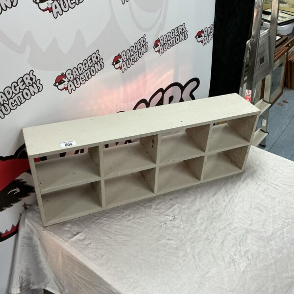 Painted wooden wall storage unit with multiple shelves for display.