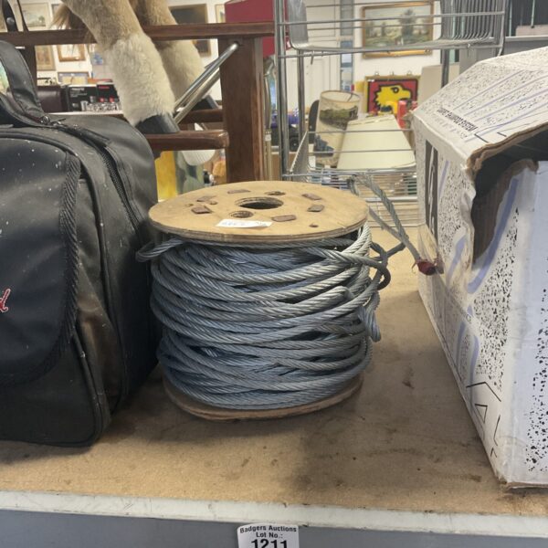 Heavy duty steel cable tightly wound on a wooden spool.