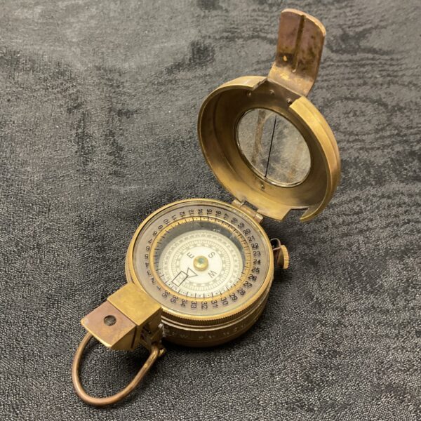 Open vintage brass compass showing the dial and needle.
