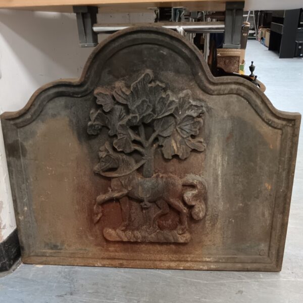 Detailed vintage cast iron fireplace back with horse and tree design.