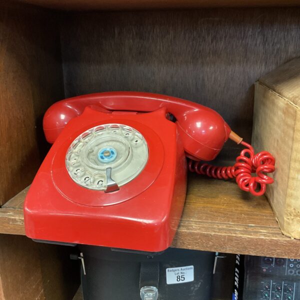 Close-up of a vintage red rotary telephone with a dial.