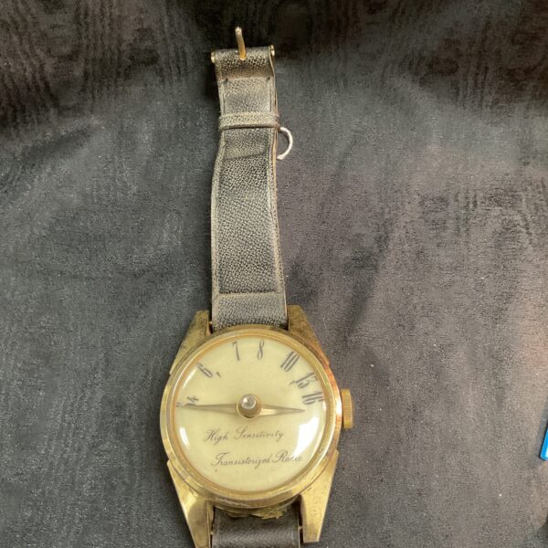 Vintage transistor wristwatch radio with large face and tuning dial.