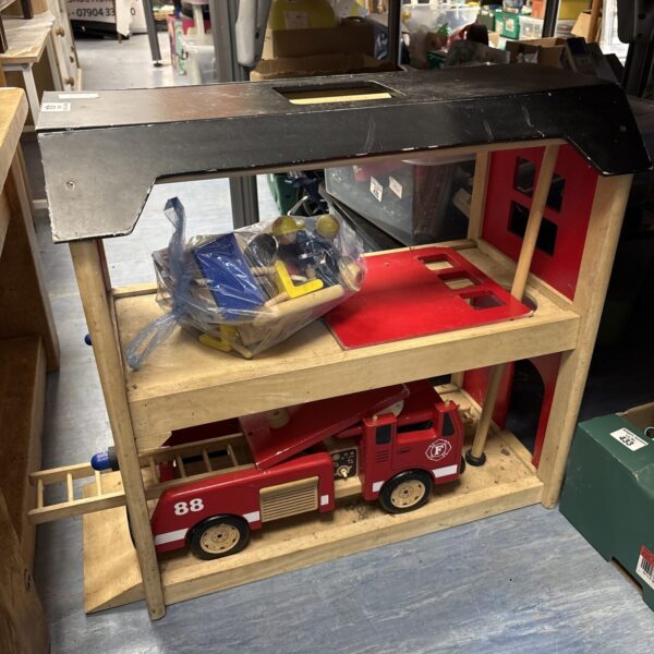 Vintage wooden fire station playset with red fire truck.