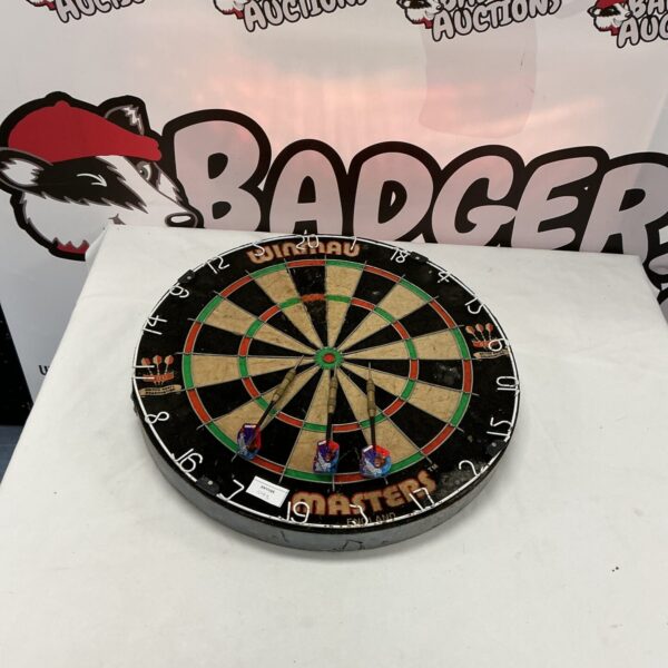 Close-up of a used Winmau dartboard with visible dart impacts.