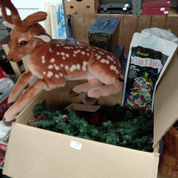 Realistic-looking plush toy of a sika deer fawn and large box Christmas decorations and lights