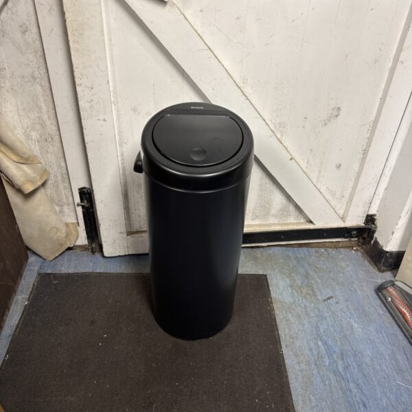 Stainless steel Brabantia push bin for kitchen waste disposal.