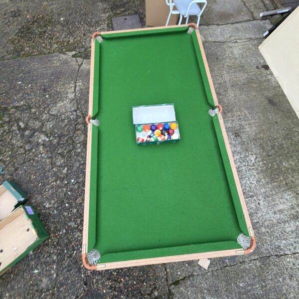 Green folding pool table with a set of pool balls.