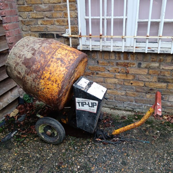 Vintage Little Benford cement mixer in a garden setting.