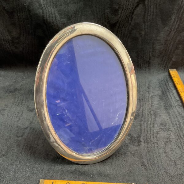 Hallmarked sterling silver oval photo frame with blue backing.