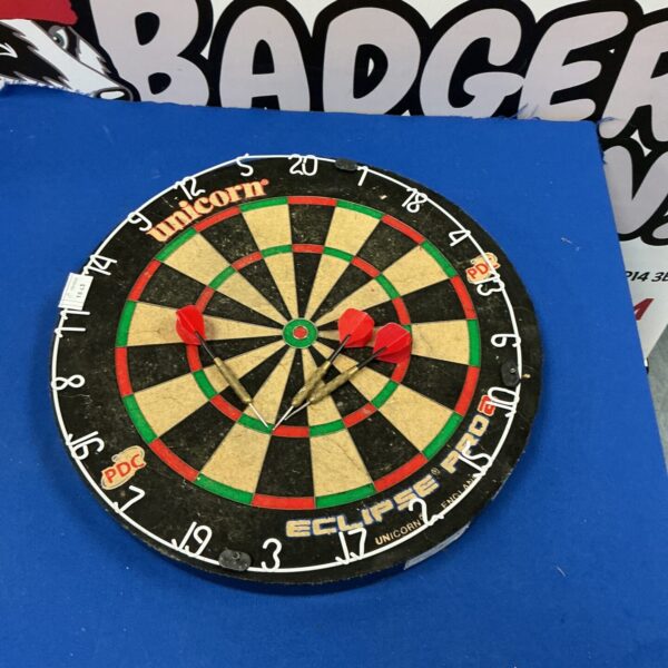 Front view of a used Unicorn Eclipse dartboard with darts.