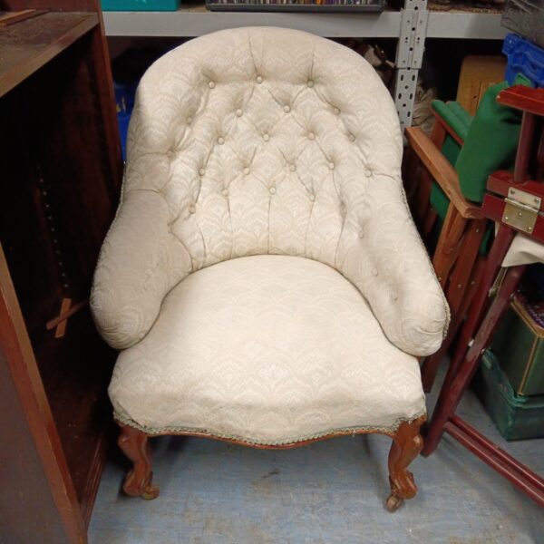 Cream coloured Victorian button back armchair with carved wooden legs.