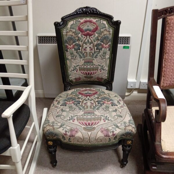 Victorian nursing chair with vibrant floral upholstery and ebonised frame.
