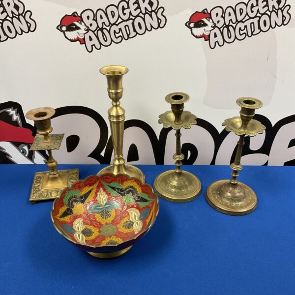Vintage brass candlesticks and Indian bowl on a dark surface.