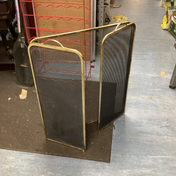 Vintage brass fire guard with mesh panel for fireplace safety.