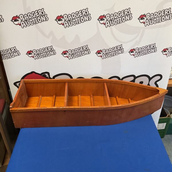 Side view of a wooden boat shaped shelf unit.