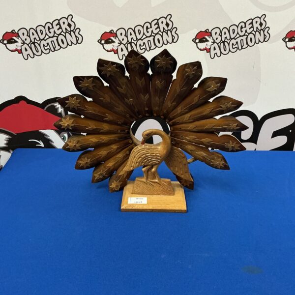 Intricately carved wooden peacock sculpture with radiating feathers.