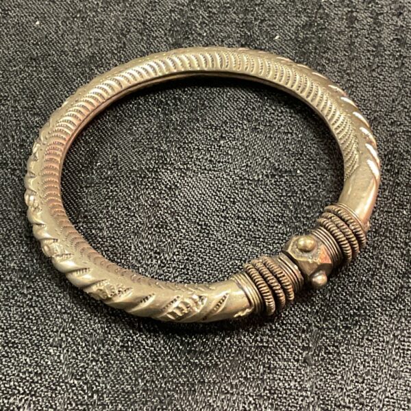 Antique Indian silver bangle with repeating patterns.