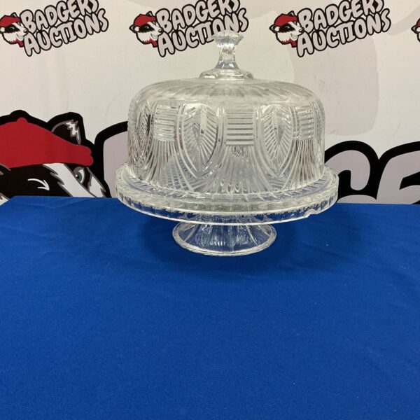 Vintage cut glass cake stand with dome on blue backdrop.