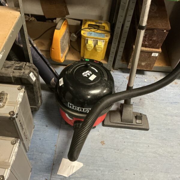 Red Numatic Henry vacuum cleaner with hose attached.