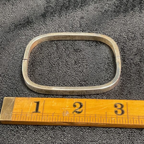 Close-up of a silver square hinged bracelet.