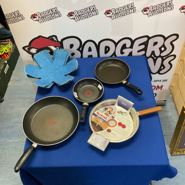 Lot of four Tefal frying pans with black handles.