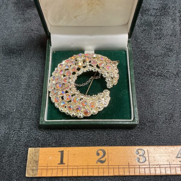 Vintage crescent brooch with multi-faceted stones in silver tone.