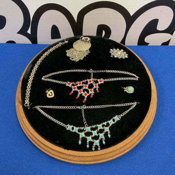 Vintage jewellery display cushion with velvet surface and jewellery.