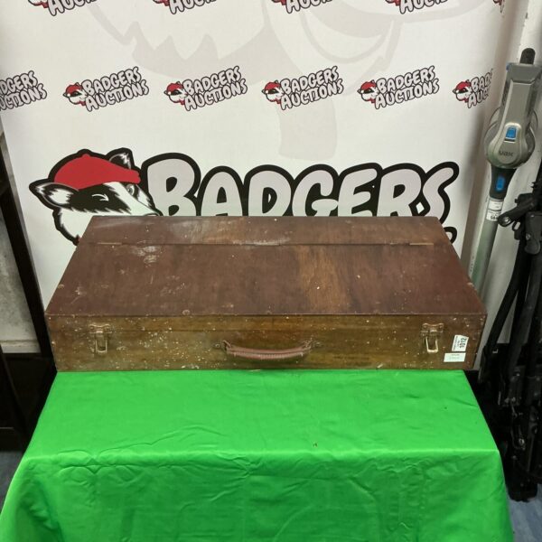 Front view of a vintage wooden tool chest on a green backdrop.