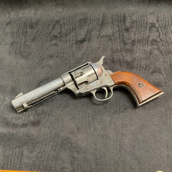 Antique percussion revolver with wooden grip, side view.