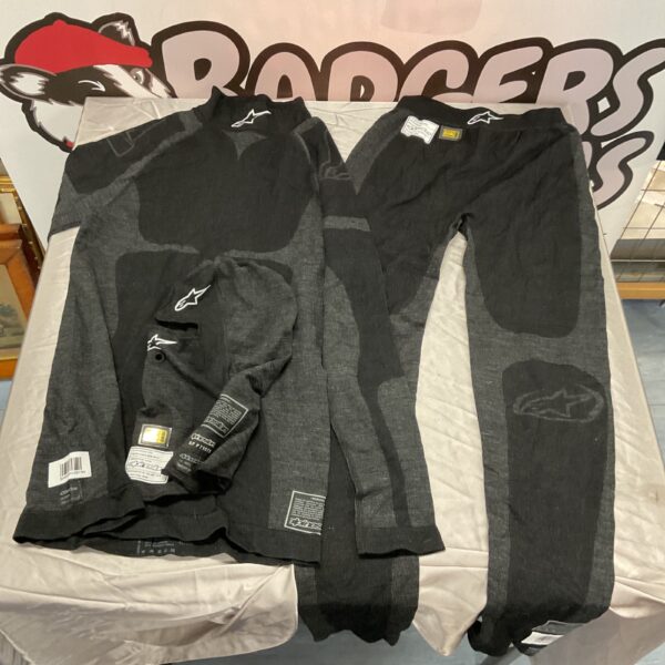Black Apinestars race suit displayed on a table, motorsport apparel.