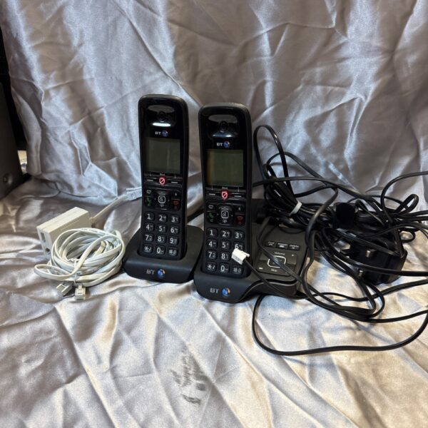 Pair of vintage BT cordless phones on a dark surface.
