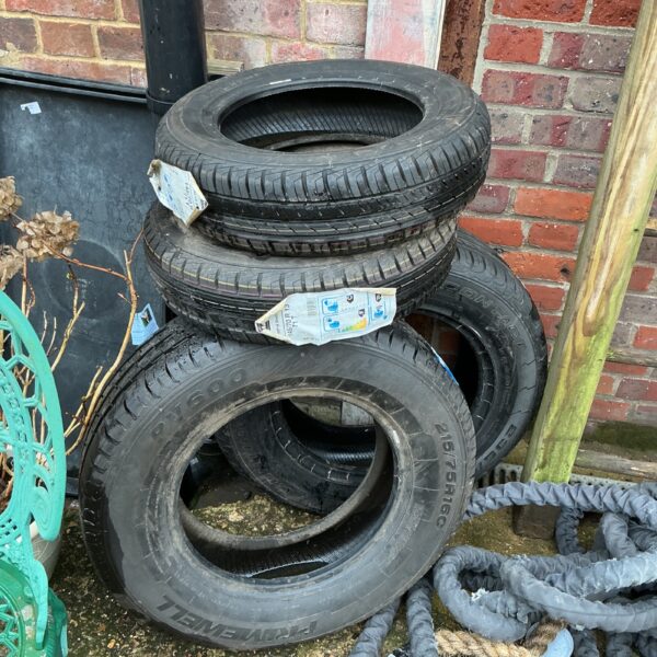 Stack of four used car tyres for automotive projects.