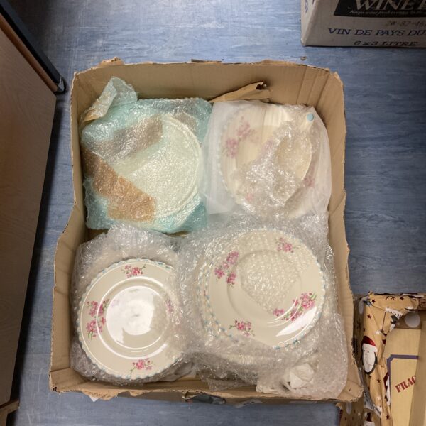 Vintage floral pattern plates in a cardboard box.