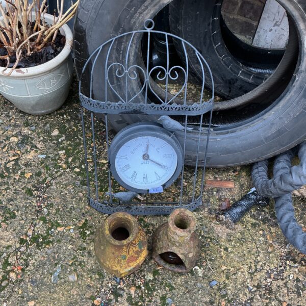 Vintage garden clock with integrated tea light holders in a garden setting.