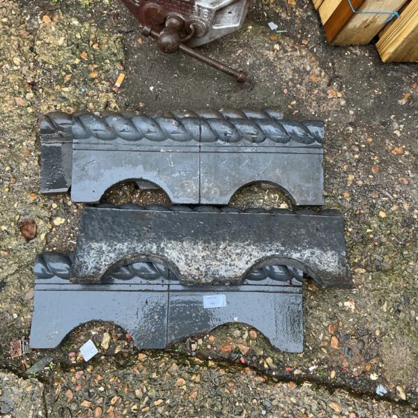 Four weathered garden edging blocks with a decorative scalloped edge.