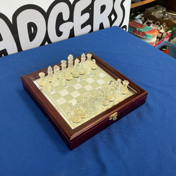 Clear glass chess set on a mirrored board in wooden case.