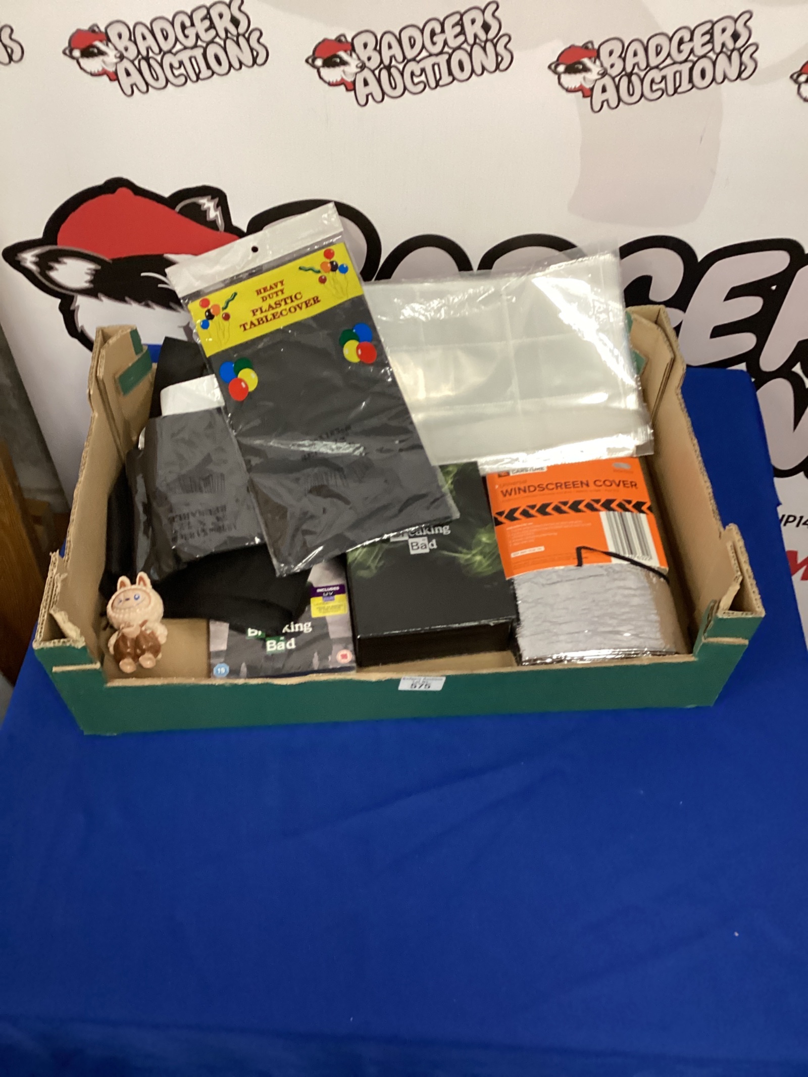 678 Box of mixed including plastic table covers breaking bad DVD box set windscreen cover and Labubu