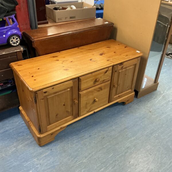 Low-level pine cupboard with doors, ideal for storage.
