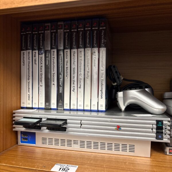 Silver PlayStation 2 console with games and controller.
