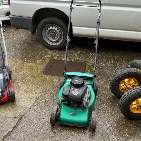 Vintage Qualcast petrol lawnmower in a garden setting.