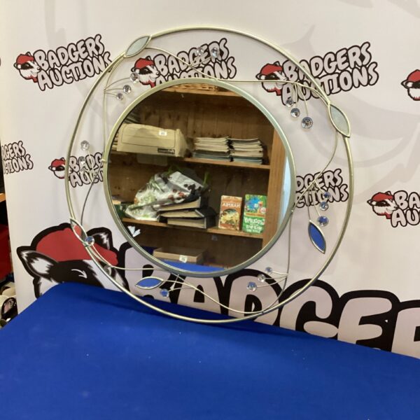 Round decorative mirror with a unique leaf pattern design.