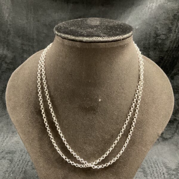 Two silver curb chain necklaces displayed on a dark background.