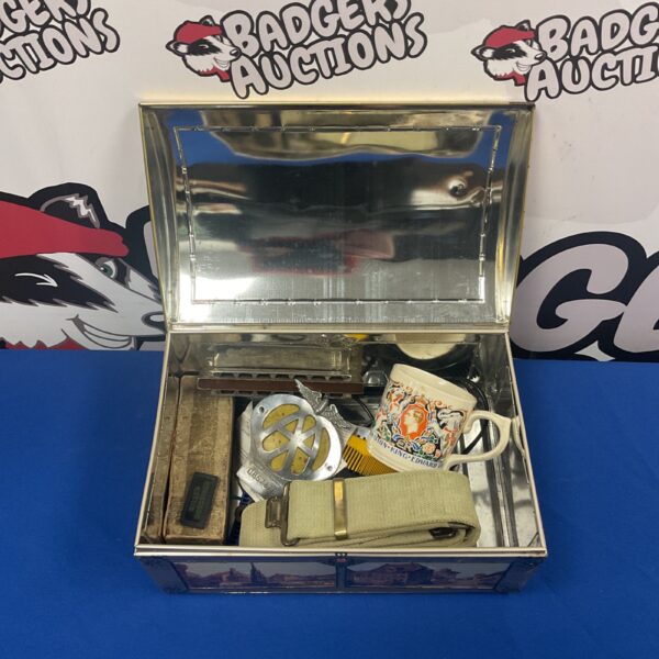 Vintage tin filled with a car badge, harmonica and dominoes.