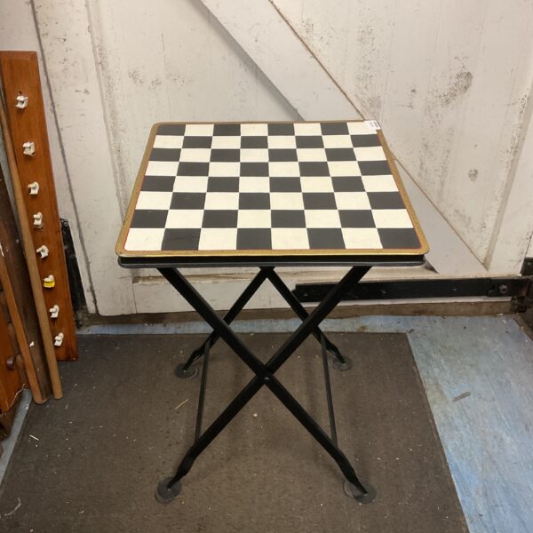 Vintage folding chessboard table with black and white checkered surface.