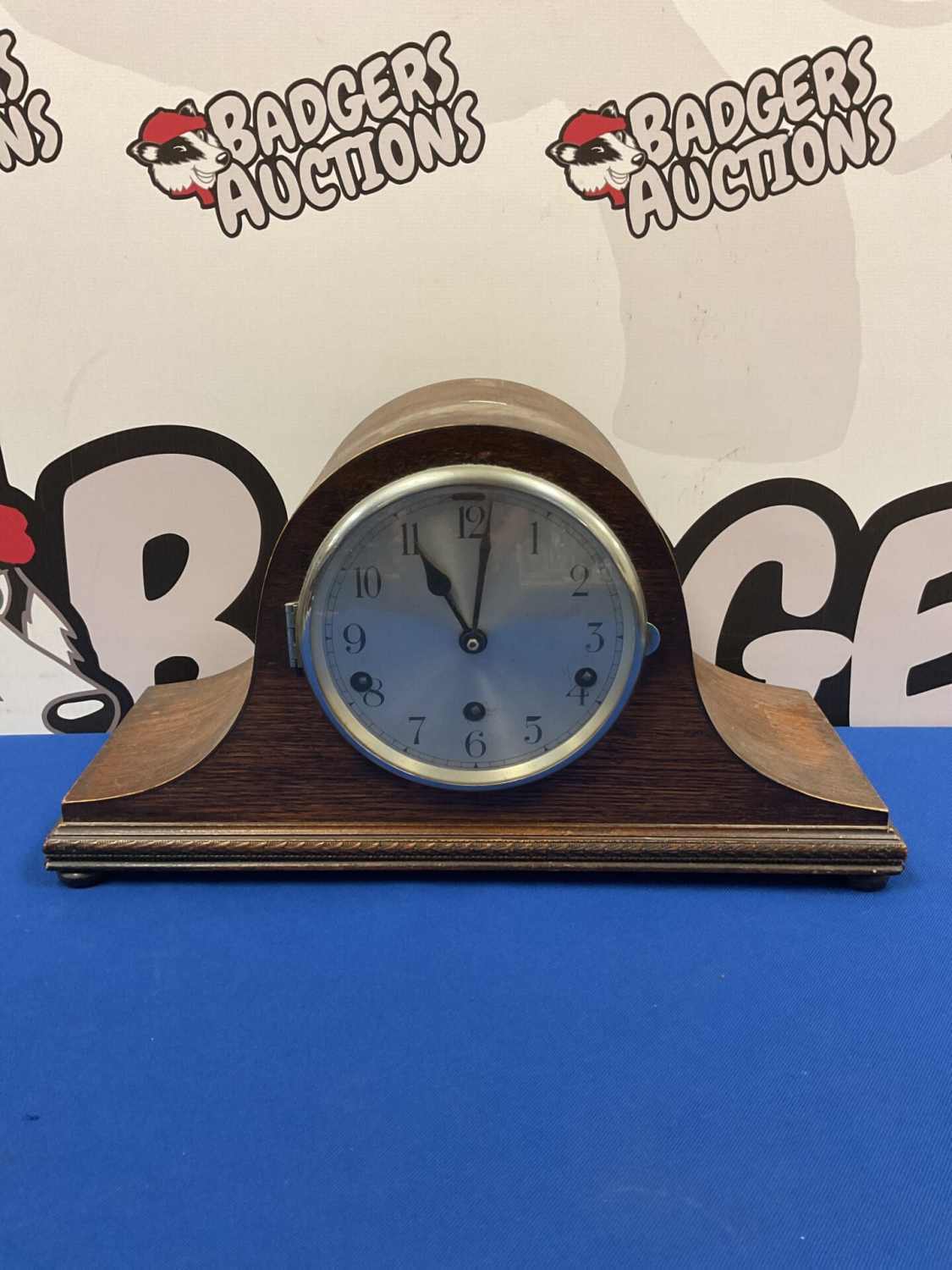 Front view of a vintage wooden mantle clock with Roman numerals.