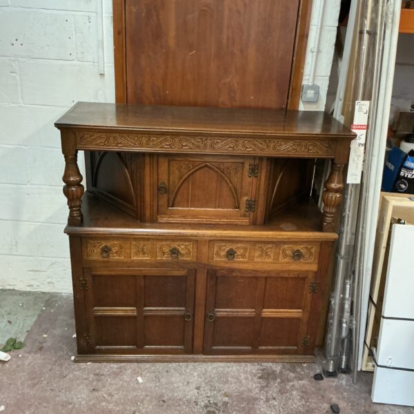 Vintage oak court cupboard with carved details and shelf storage.