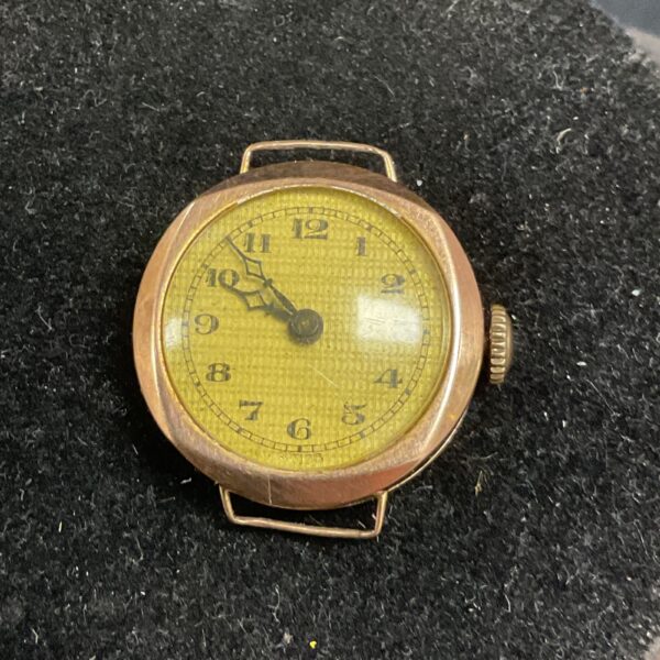 Vintage rose gold wristwatch with a yellow dial.